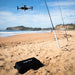 Aeroo Pro Drone flying over beach with fishing rods and carry case