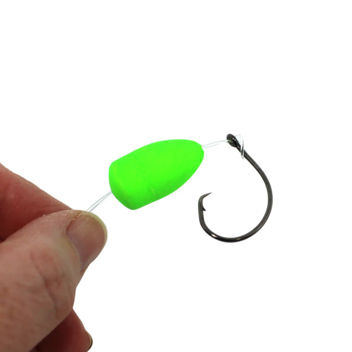 A close-up of a fishing lure with a bright neon green bead and a black metal hook, held by a person's fingers against a white background.