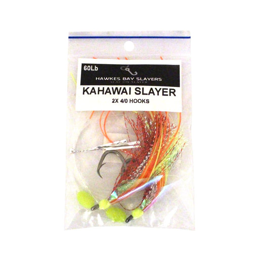 A packaged fishing lure set in a clear plastic bag with a white label reading 'Hawkes Bay Slayers' and 'Kahawai Slayer 2x 4/0 Hooks'. The lure features orange, red, green, and yellow skirted strands with a silver metal jig head and hooks.