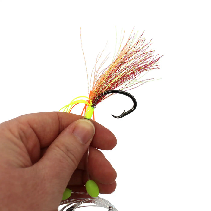 A close-up of a fishing lure being held by a person's hand against a plain white background. The lure has a black hook, neon yellow-green beads, and a skirt made of orange, red, and yellow strands.