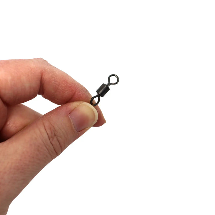 A close-up of a person's hand holding a small black metal swivel clasp against a plain white background.