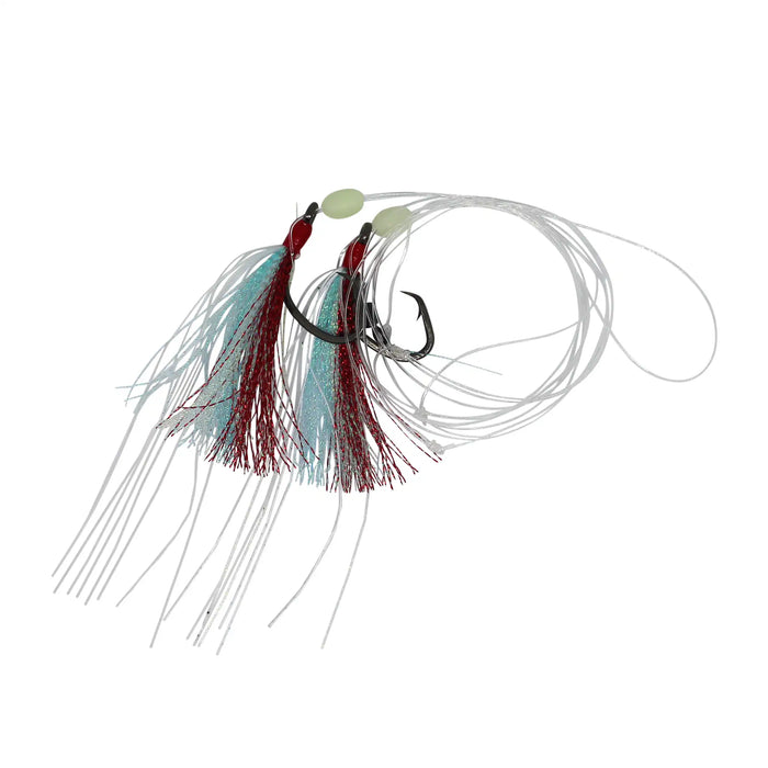 A fishing jig lure with two treble hooks, featuring a silver spinner blade, light green beads, and two tinsel skirts in red and light blue, suspended on white line against a white background.