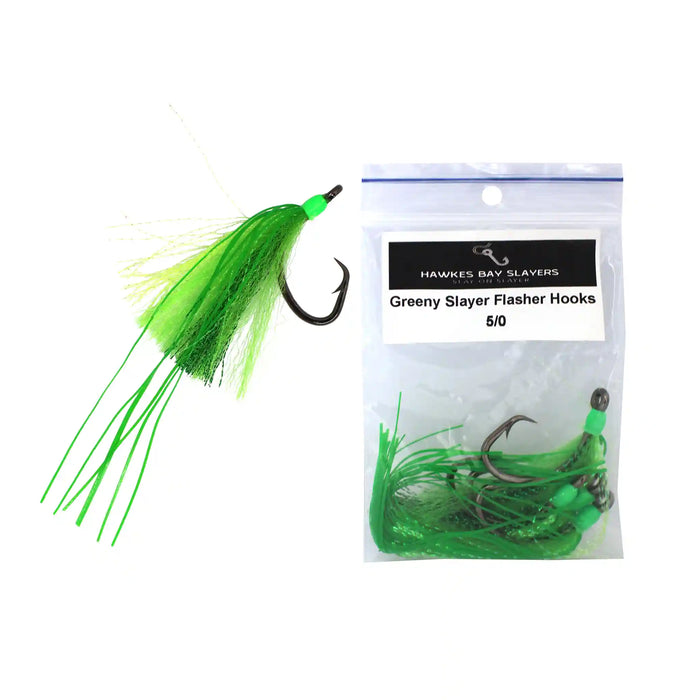 A green fly fishing lure with a black hook and bright green skirt is shown next to a clear plastic bag labeled 'Hawkes Bay Slayers Greeny Slayer Flasher Hooks 6/0' on a white background.