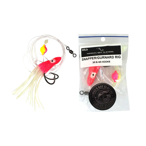 A Snapper Gurnard fishing jig rig set shown next to its retail packaging. The product features a bright pink/red topwater jig with a yellow and orange bubble, a white skirt, and a black treble hook.